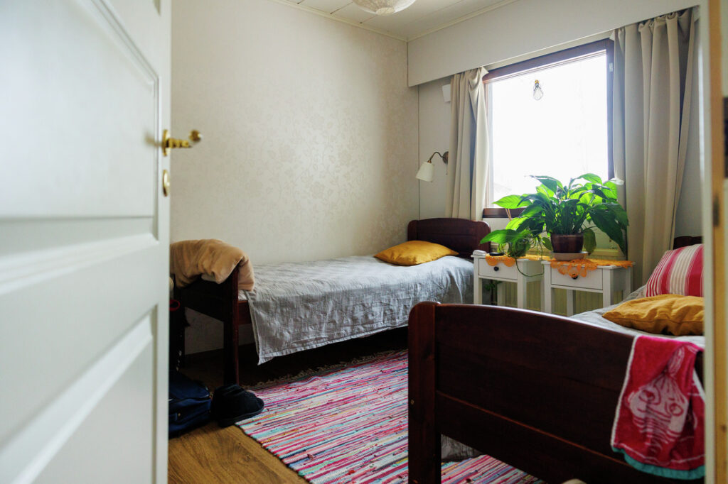 Asuinhuone perhehoitopaikassa. Huoneessa kaksi pedattua sänkylä. Tuolilla on asiakkaan tavaroita.