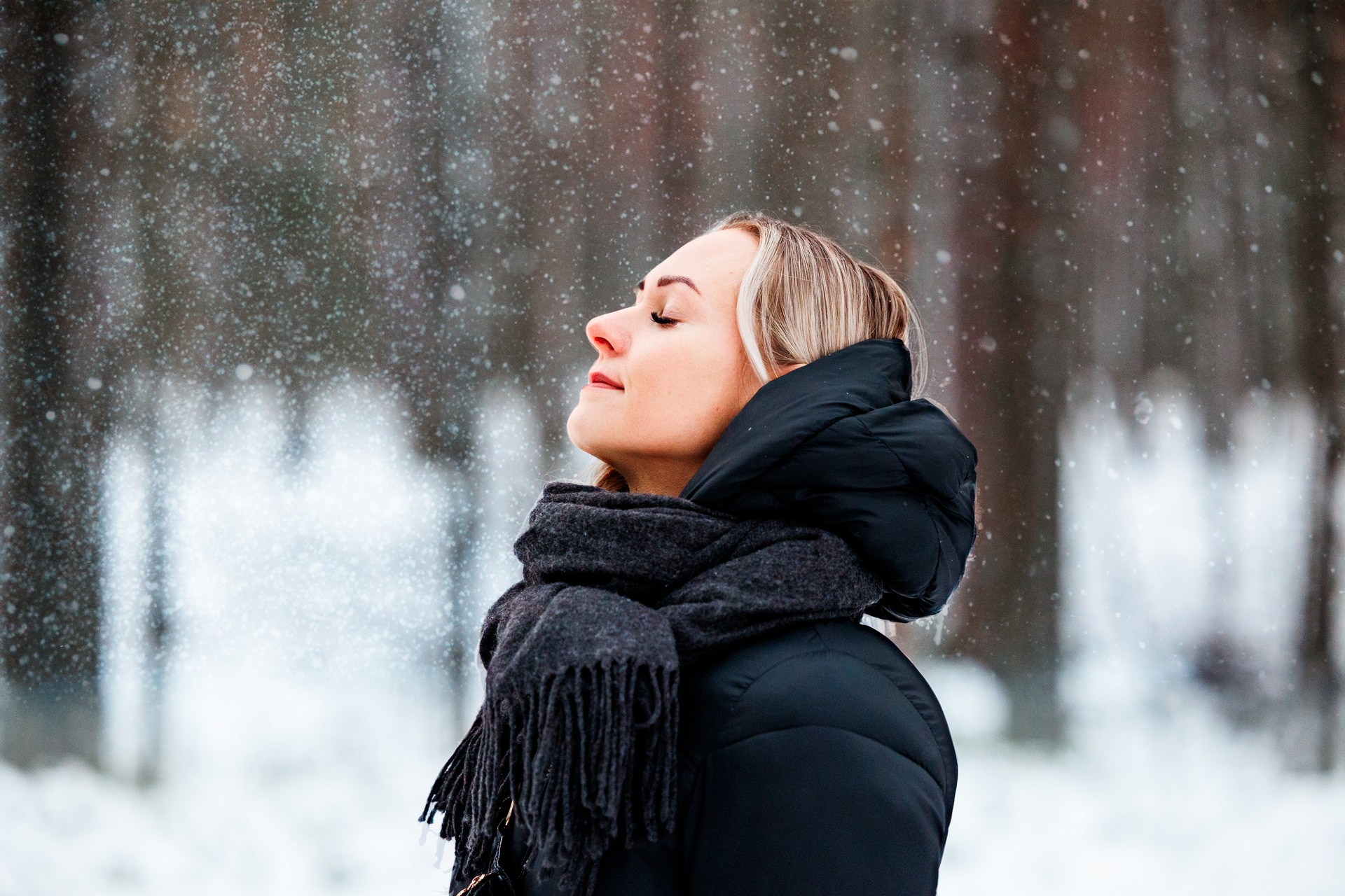 Henkilö seisoo talvsisessa metsässä ja katsoo ylös päin.
