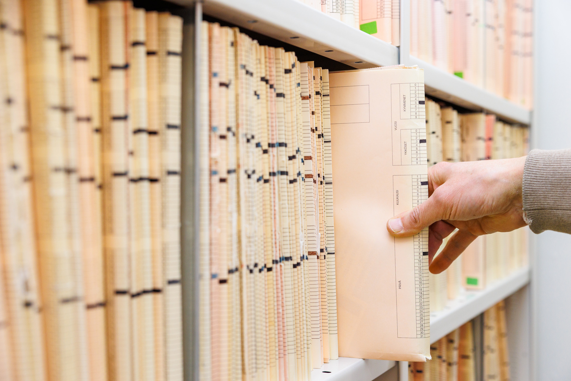 Potilasarkistossa otetaan potilaan kansiota arkisto hyllystä.