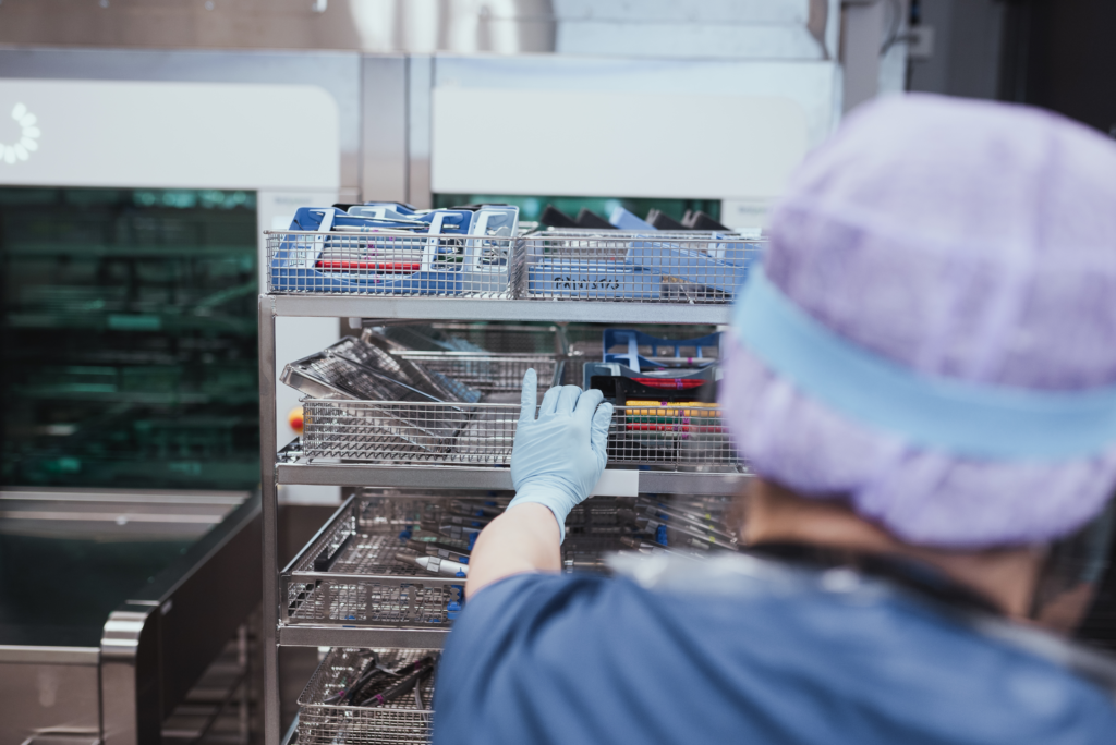 Välinehuollon ammattilainen pitää kättään välinehyllyn reunassa.