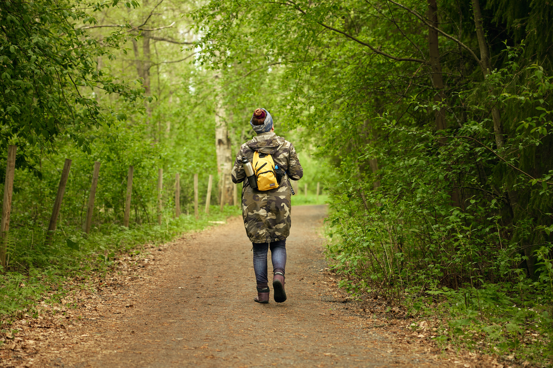Henkilö kävelee hiekkatiellä metsän keskellä.
